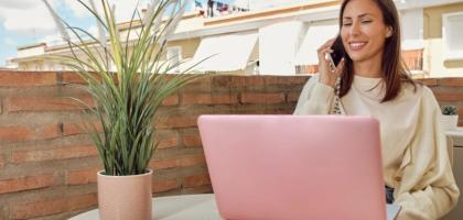 Femme qui téléphone devant son ordinateur sur son balcon